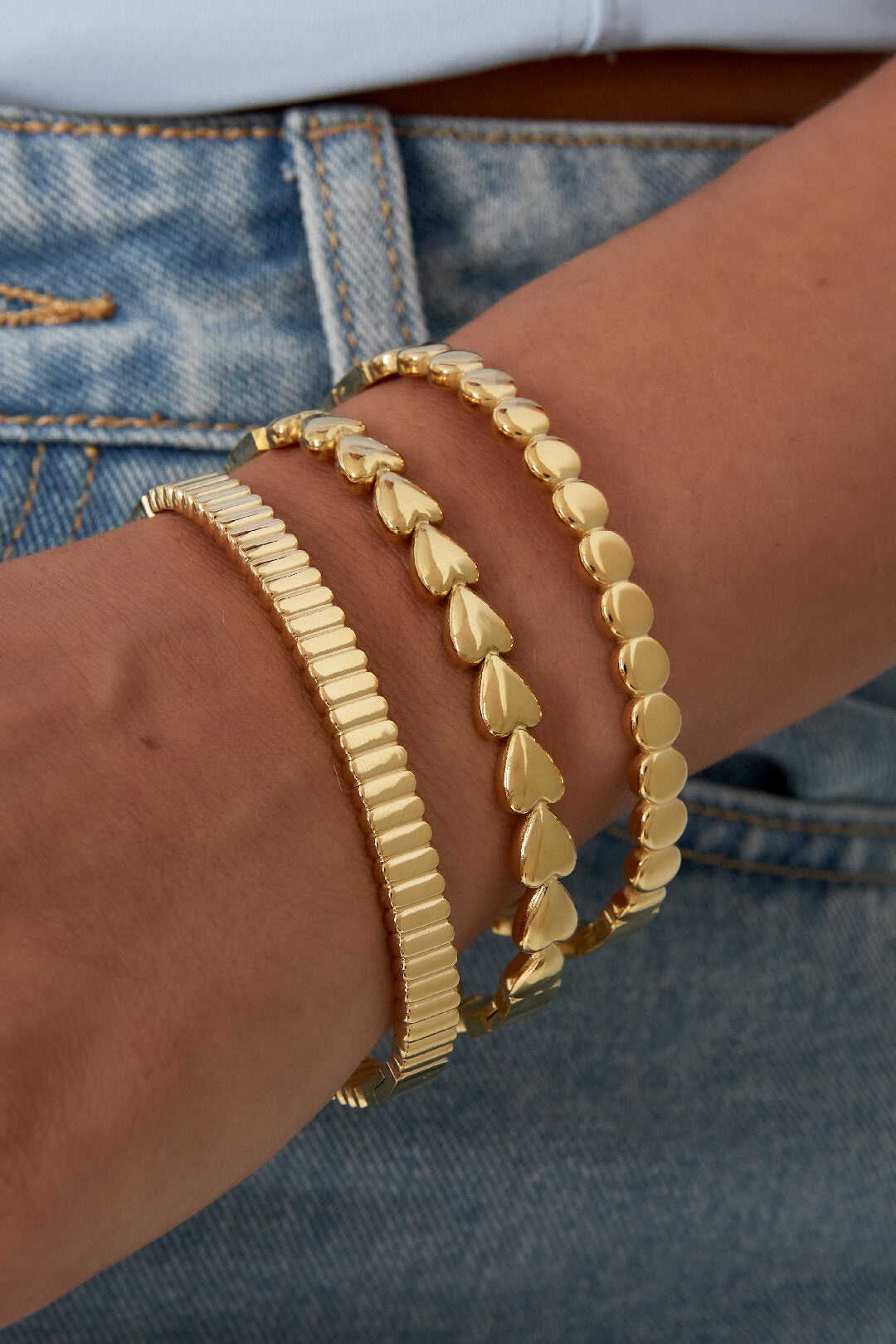 Stijlvolle goudkleurige armbandenset van 3 met verschillende ontwerpen op de pols